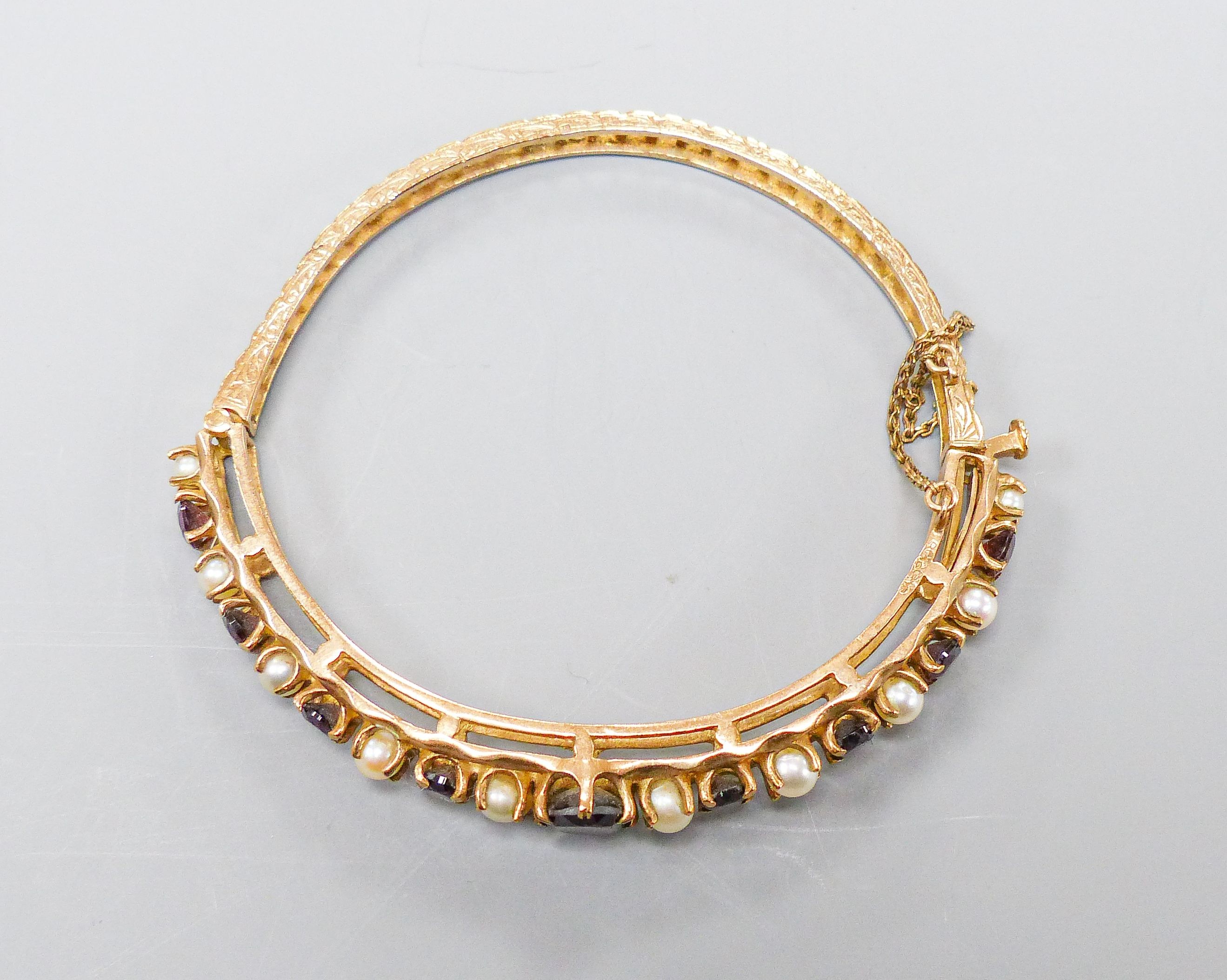 A 9ct gold, garnet and cultured pearl set hinged bracelet, gross weight 16.1 grams.